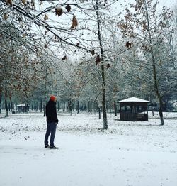 Man standing on snow covered field against bare trees