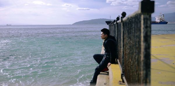 Woman standing by sea against sky