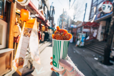 Cropped hand holding food over street