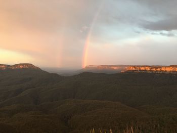 Scenic view of rainbow over landscape against sky