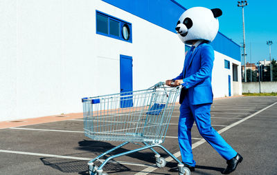 Rear view of man with shopping cart on road