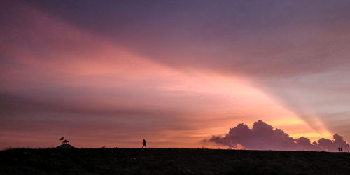Scenic view of silhouette field against sky during sunset
