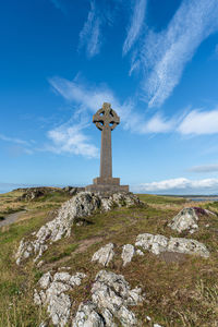 Cross on rock against sky