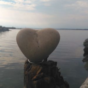 Close-up of heart shape by sea against sky