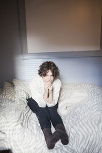 Young woman sitting on bed at home