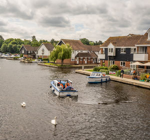 Houses by river amidst buildings against sky