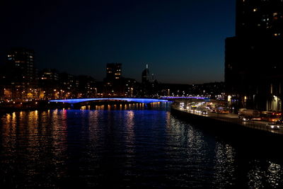 Illuminated bridge over river in city at night