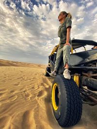 Full length of woman standing on beach buggy at desert