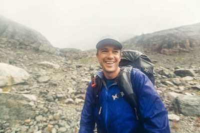 Backpacker smiling despite bad weather, rain and wind.