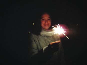 Portrait of man holding sparkler at night