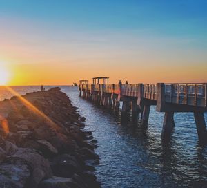 Pier over sea against sky during sunset