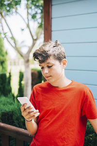 Teenage boy using phone at yard