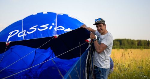 Portrait of young man putting up tent on field