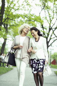 Happy senior female friends walking on garden path