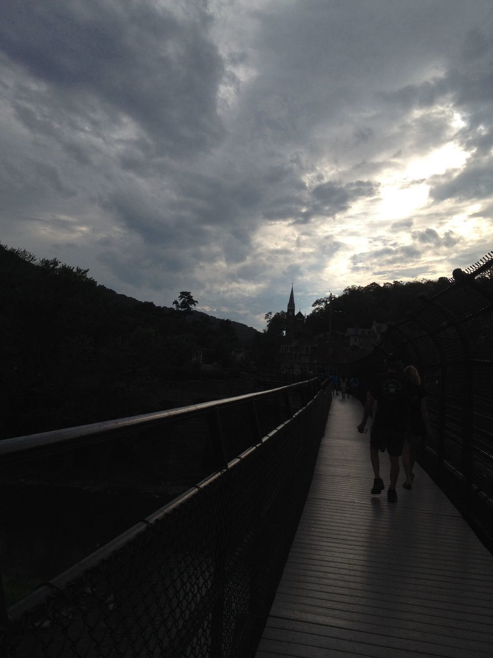 walking, sky, the way forward, lifestyles, men, leisure activity, person, full length, railing, built structure, diminishing perspective, architecture, cloud - sky, vanishing point, rear view, connection, tree, sunset