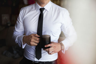 Midsection of man holding coffee cup
