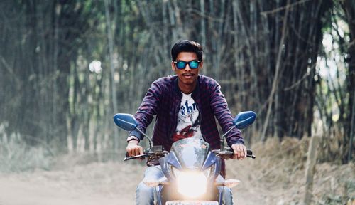 Portrait of young man riding bicycle in forest