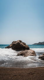 Rocks on beach against clear sky