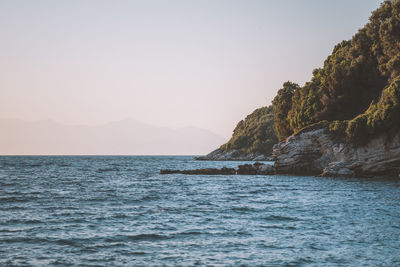 Scenic view of sea and mountains against clear sky