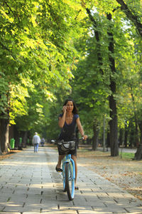 Woman riding bicycle on footpath at park