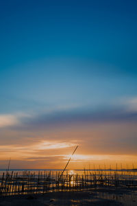 Silhouette pier over sea against sky during sunset