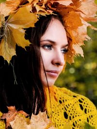 Close-up of woman wearing autumn leaves