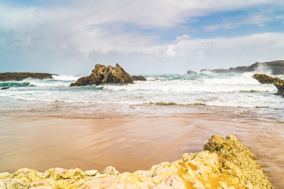 Rock formation on beach against sky