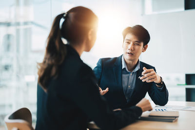 Side view of woman using mobile phone while sitting on table