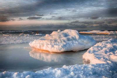 Scenic view of frozen sea against cloudy sky during sunset