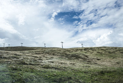 Wind turbines on field against cloudy sky