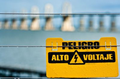 Close-up of yellow information sign against sky