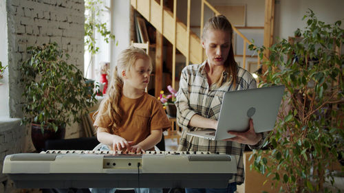 Mother and daughter doing high five by piano