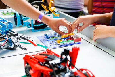 Children hands holding ready made robots on table joyful smart whizzkid experimenting with humanoid