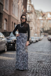 Fashionable woman standing on footpath in city