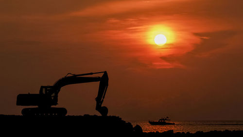 Silhouette construction site against sky during sunset