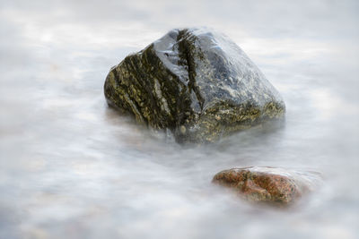 Close-up of rock formation in water against sky