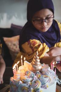 Girl burning birthday candles on cake