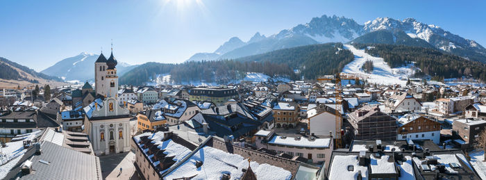 Panoramic view of town against mountains on sunny day during winter