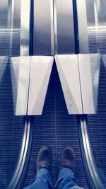 Low section of a man standing on escalator