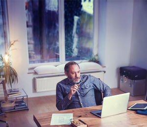 Full length of a man using mobile phone at table