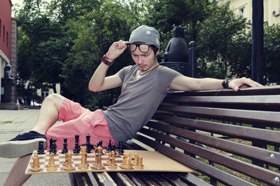 Man playing chess while sitting on bench at park