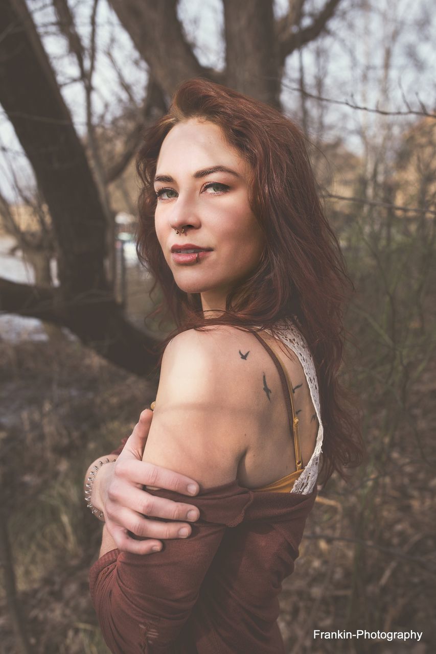 PORTRAIT OF YOUNG WOMAN STANDING ON TREE