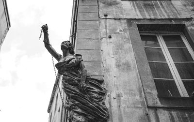 Low angle view of statue against building. she raises her fist to the sky like a sign of protest