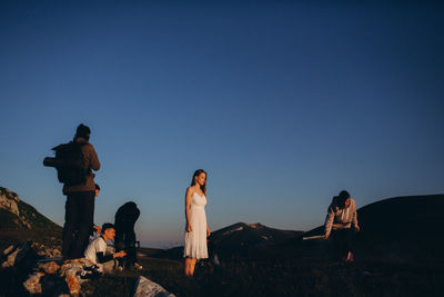 People on field against clear blue sky