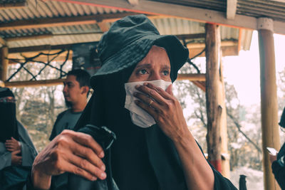 Woman wearing mask looking away while standing outdoors