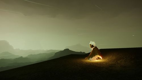 Woman standing on illuminated land against sky