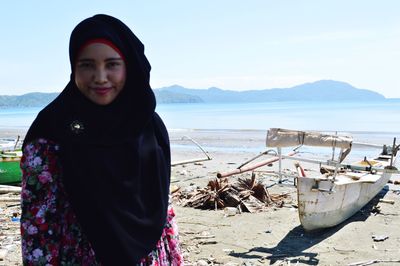 Portrait of smiling woman standing at beach against sky