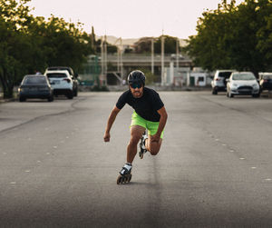 Full length of man inline skating on street against trees