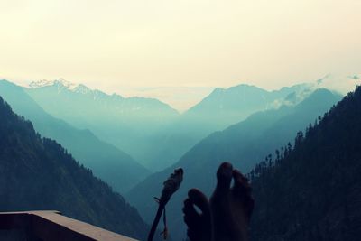 Low section of woman photographing mountains against clear sky