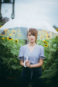 Young woman looking down while standing against plants